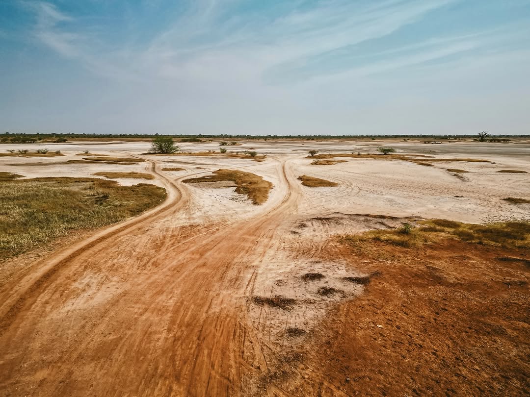 Pistes ocre traversant la savane sénégalaise sous un grand ciel, grands espaces