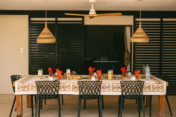 Salle à manger : grande table dressée, lanternes en osier et tentures africaines
