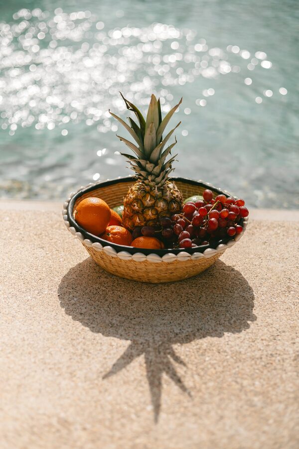 Corbeille de fruits frais ananas, raisins et clémentines au bord de la piscine