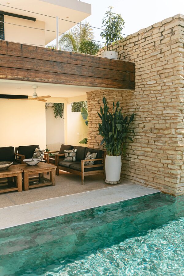 Salon extérieur sous la terrasse en bois face à la piscine et au jardin
